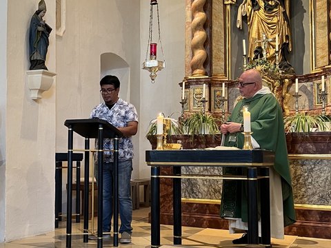 Gottesdienst in der Kirche des Jugendhauses St. Anna: Ein Teilnehmer liest am Pult, während P. Ulrich im grünen Messgewand am Altar steht.