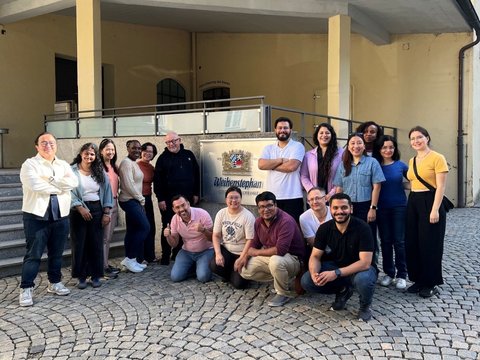 Gruppenfoto der Seminargruppe vor der Staatsbrauerei Weihenstephan. Die Personen stehen und knien auf einem gepflasterten Platz neben dem Brauereischild.