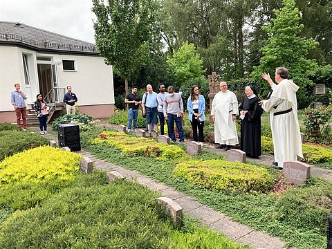 Pater Thomas und Pater Ulrich mit der Gruppe bei der Besichtigung des Kloster-Friedhofs