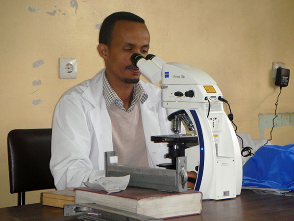Globale Gesundheit - ein Mann schaut in ein Mikroskop